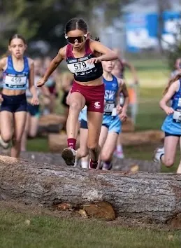 Chloe competing in cross country and clearing a log obstacle