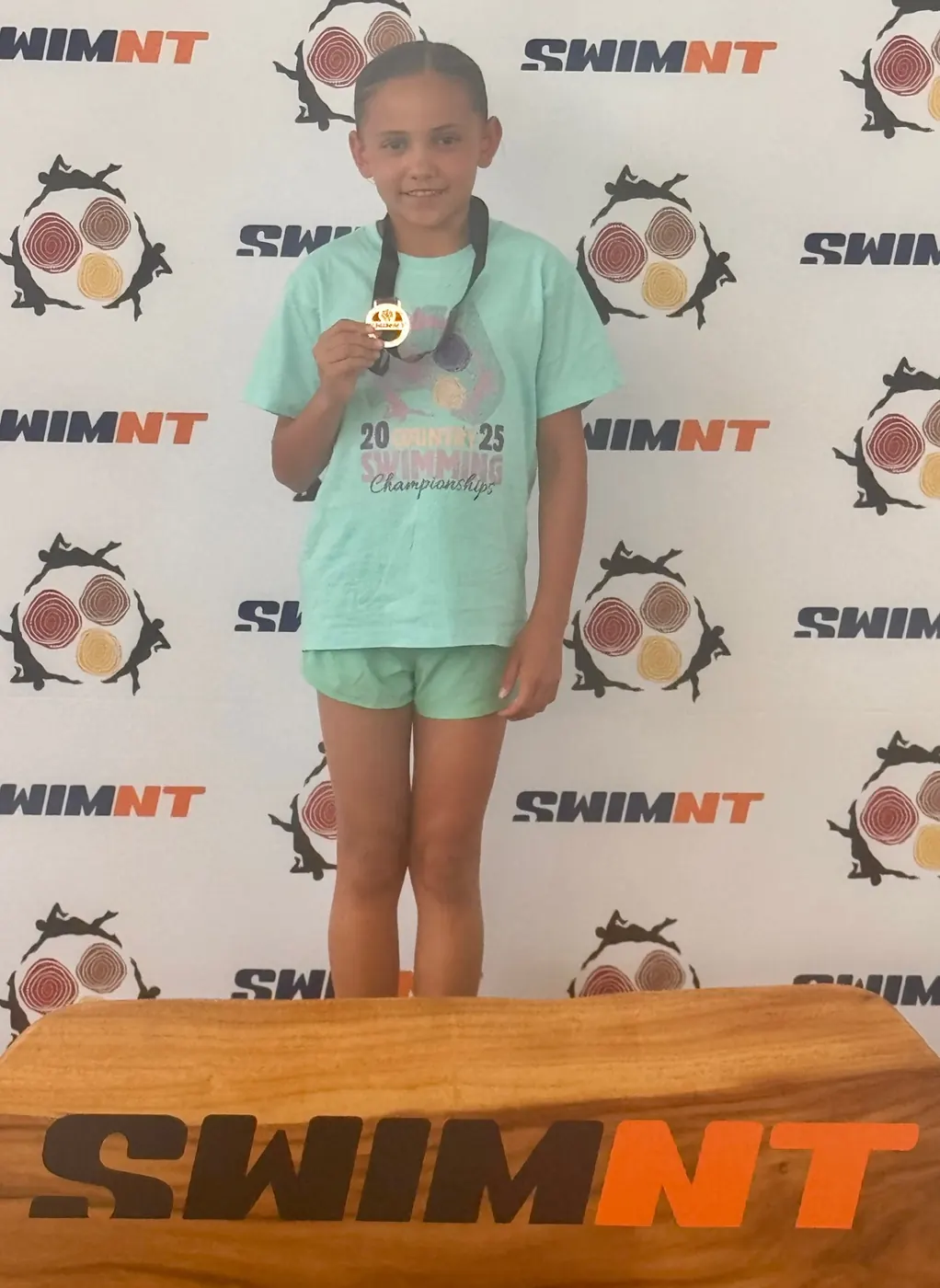 Chloe holding a swimming medal at the 2025 Northern Territory swimming championships